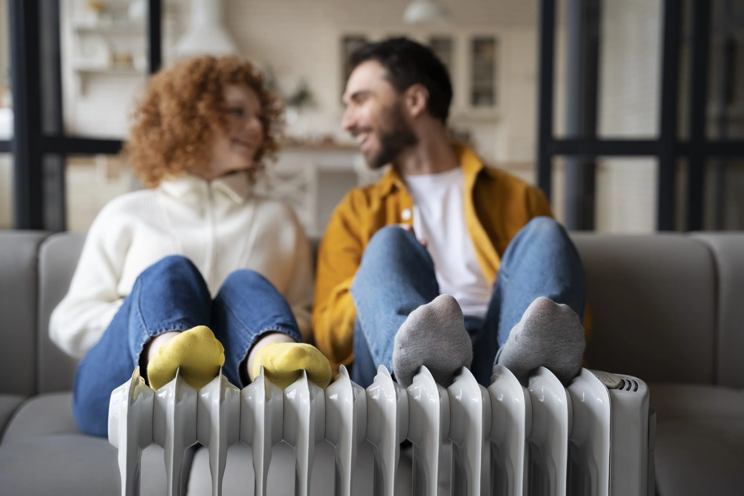 full-shot-smiley-couple-warming-up-near-heater